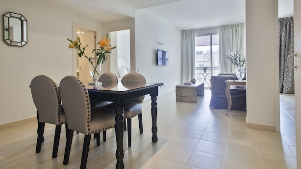 A dining area with a table and chairs, a vase with flowers, and a television on the wall. - Splendom Suites Pau Claris (Barcelona)