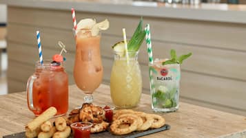 A table with three drinks, a plate of chicken wings, and a plate of pretzels.