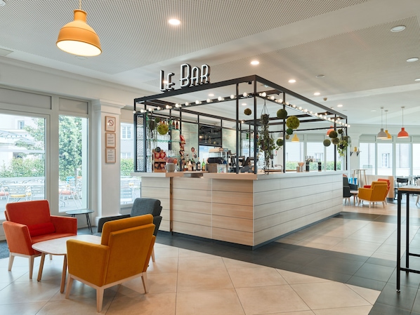 A modern bar area with a counter, seating, and a ceiling with a perforated design.