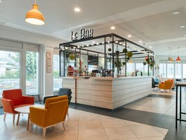 Un bar moderno con barra, asientos y techo de diseño perforado.