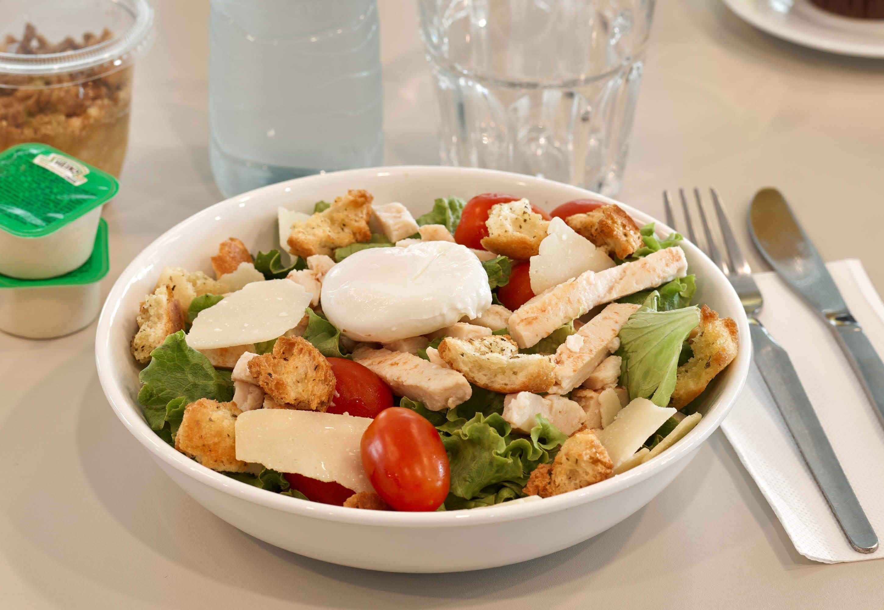 A bowl of salad with lettuce, tomatoes, croutons, and a slice of cheese.