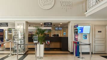 Et hotellets receptionsområde med en indtjekningsdisk, en skiltning til skranke og forud-check-in samt et velkomstskilt.