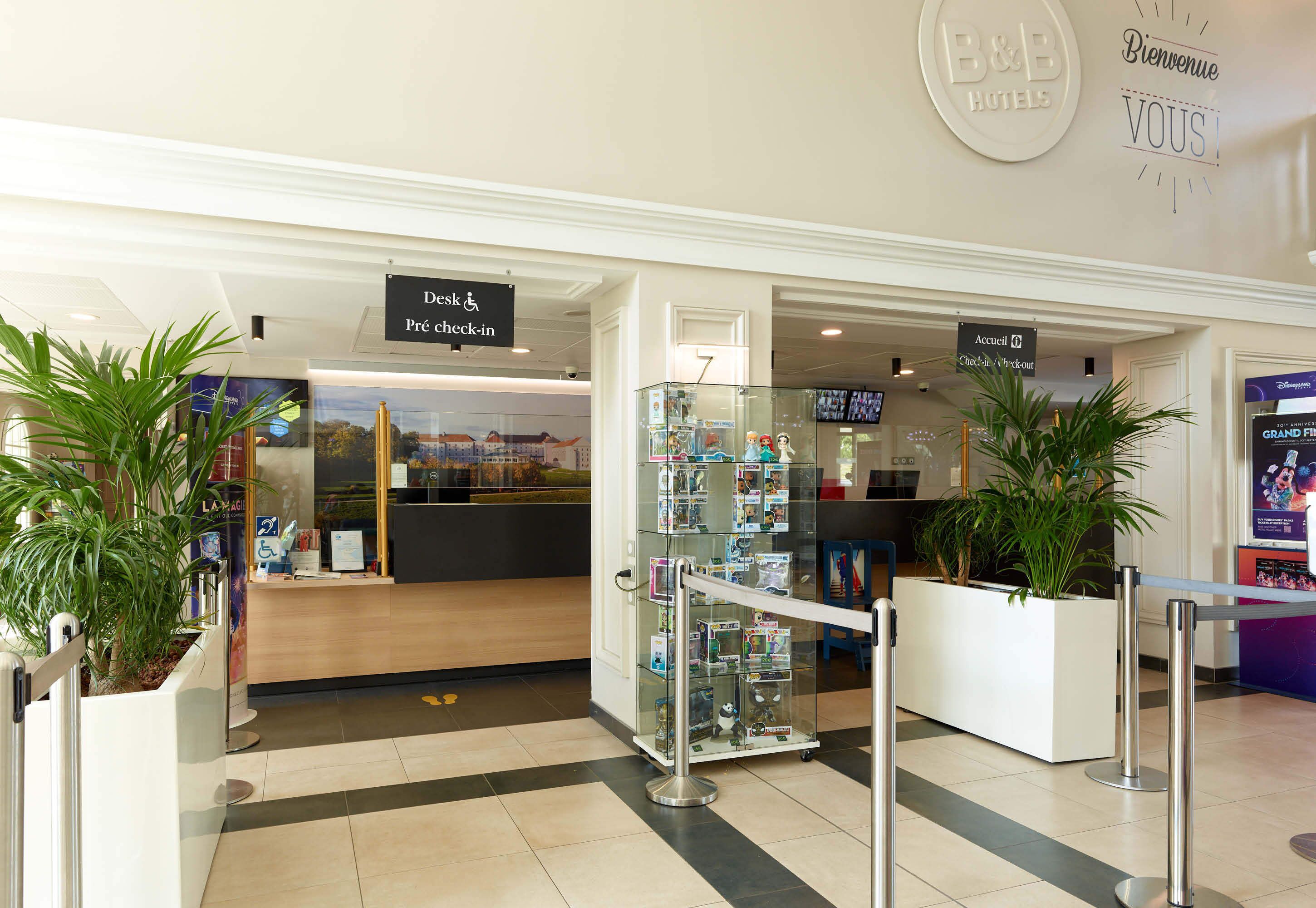 Zona de recepción de hotel con una vitrina de cristal, un mostrador de recepción y un letrero que indica la disponibilidad de habitaciones.