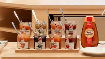 Una presentación de diversas conservas de frutas con etiquetas y cucharas, además de una botella de miel.