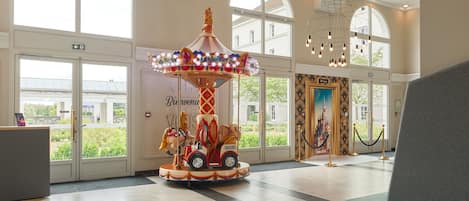 A carousel in a lobby with large windows and a reception desk.