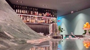 A bar area with a marble counter, bottles of alcohol, and a bowl of fruit. - Hotel Al Caminetto – Adults Only, WorldHotels Crafted (Torri del Benaco)