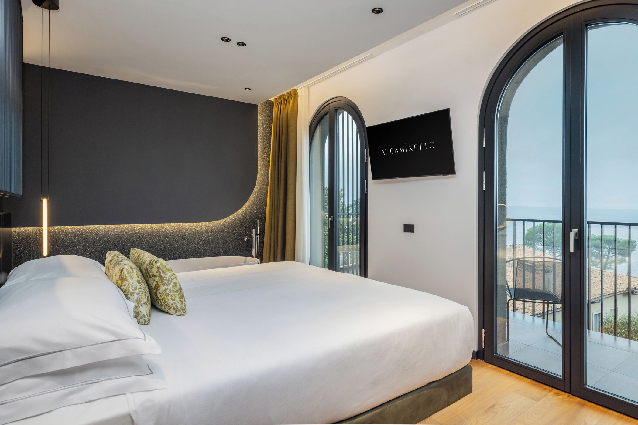 Ein modernes Schlafzimmer mit einem großen Bett, einem Fernseher und einem Balkon mit Blick.