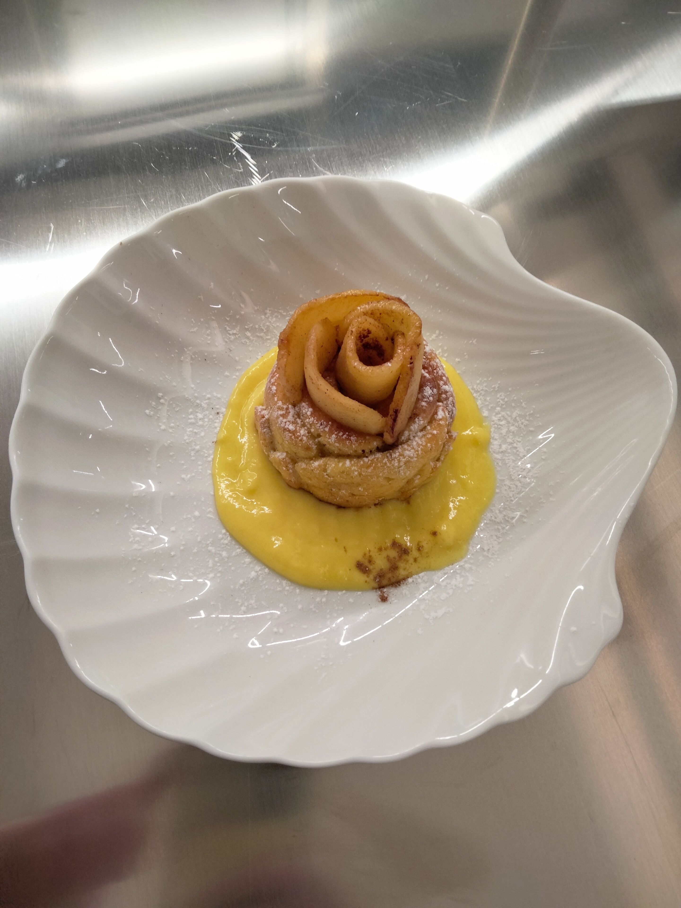 Dessert på en hvid tallerken med gul sauce og flormelis.