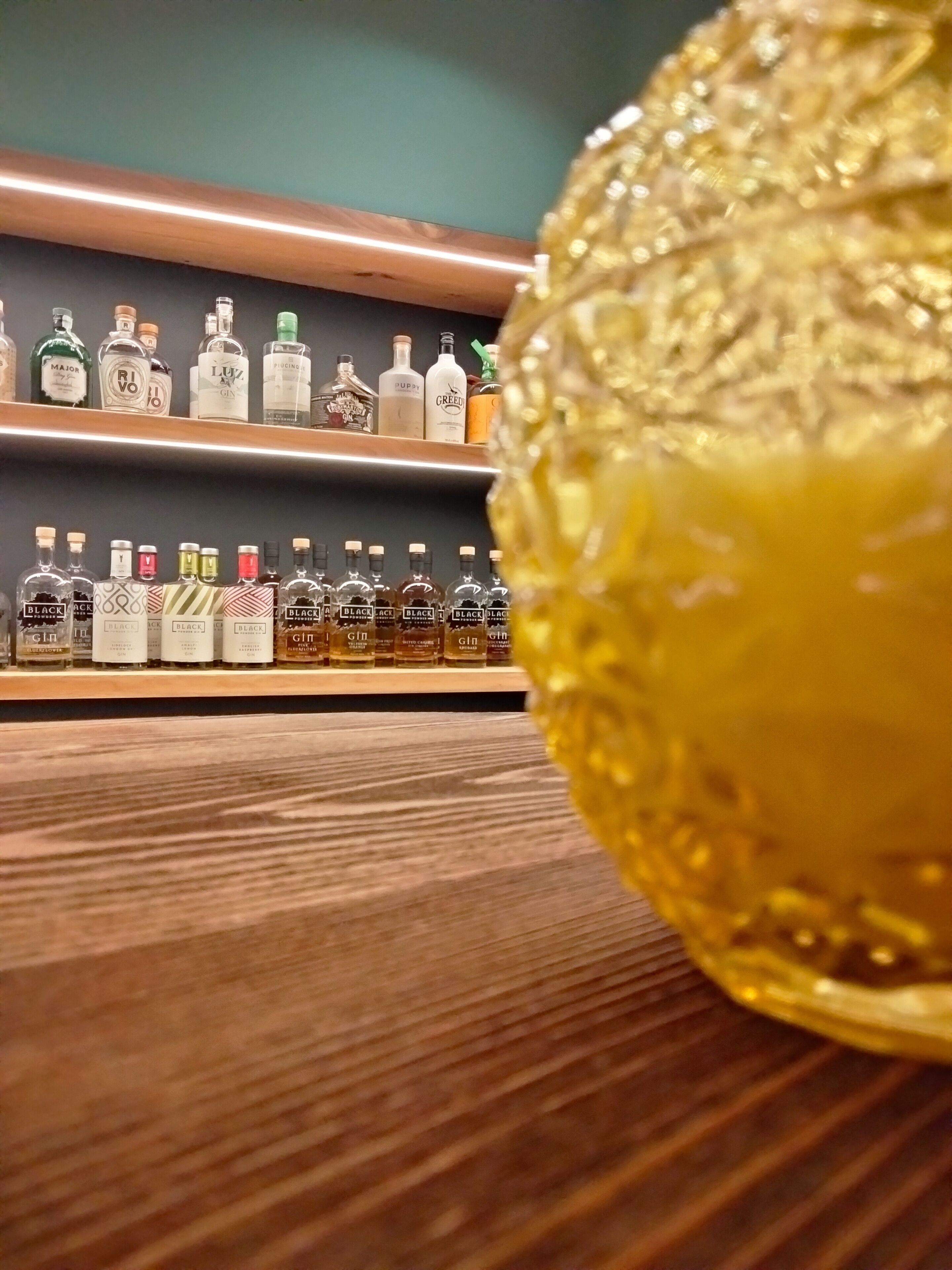 A bar area with shelves of liquor bottles and a large golden decorative sphere.