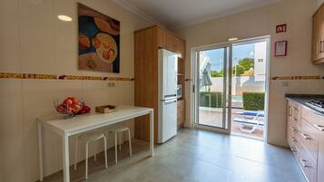 A modern kitchen with a white countertop, wooden cabinets, and a dining area with stools.