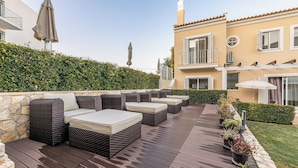 A patio with outdoor seating, a stone wall, and a hedge. - Boutique e Villas Boliqueime (Loulé)