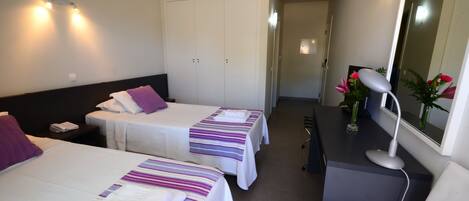 A hotel room with two beds, a desk, a chair, a mirror, and a nightstand.