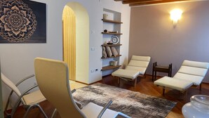A modern living room with a wooden ceiling, a large wall art piece, a sofa, two lounge chairs, a coffee table, and a rug. - Corte Uccellanda (Monzambano)