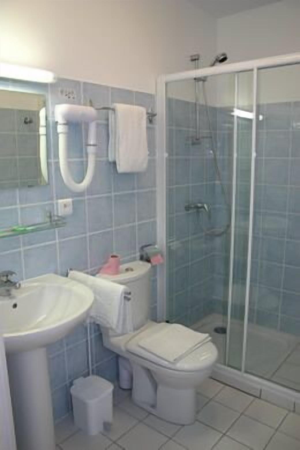 A bathroom with a sink, toilet, and glass-enclosed shower.