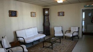 A living room with a sofa, two armchairs, a coffee table, a rug, a clock, and framed artwork on the walls. - Hôtel du Marché (Beauvoir-sur-Mer)