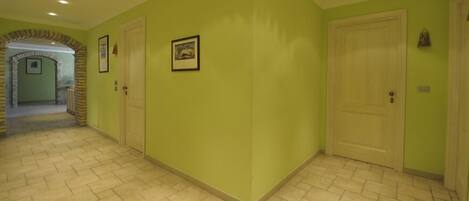 Un couloir avec un mur vert, une porte et un tableau encadré.