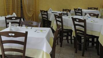 Un espace repas comprenant plusieurs tables et chaises, chacune recouverte d’une nappe blanche.