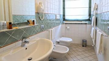 A bathroom with a sink, toilet, and a window.