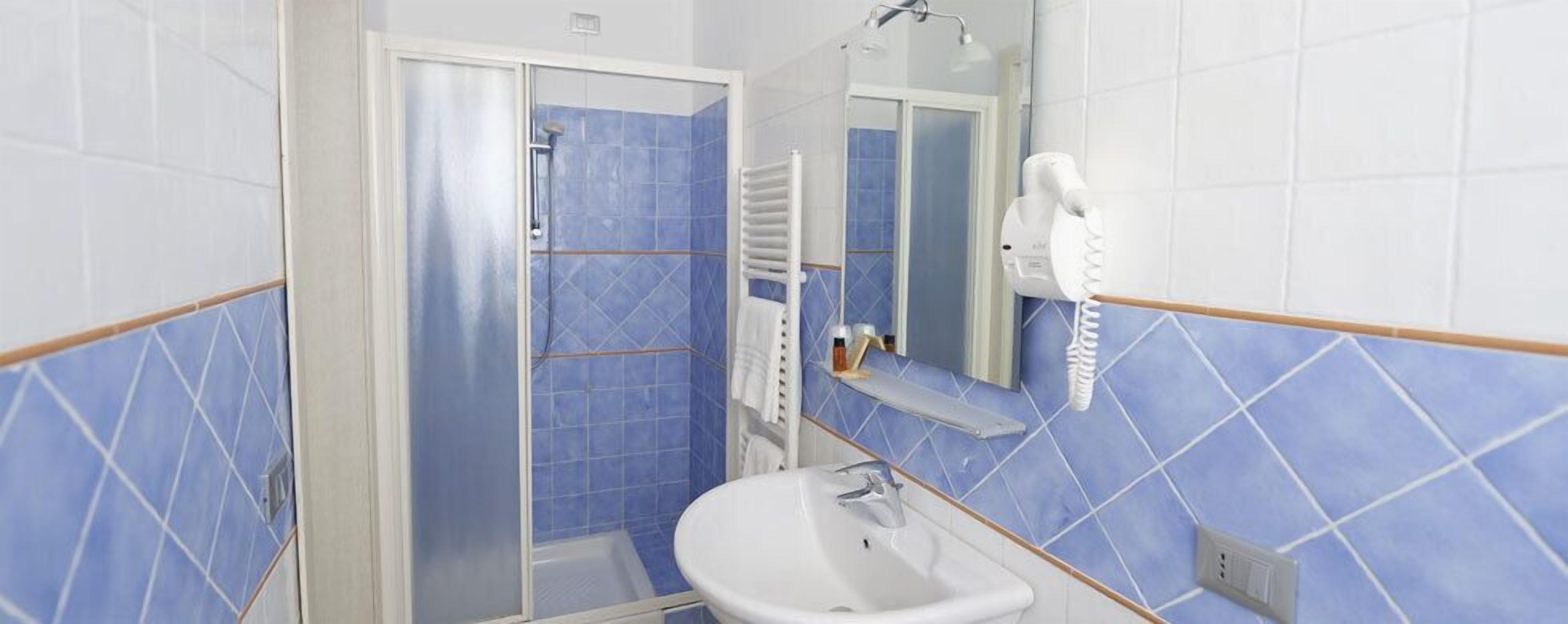 A bathroom with a shower, a sink, and a mirror.