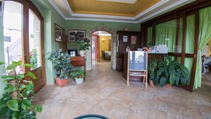 A lobby with a reception desk, a dining area, and several potted plants. - Il Vecchio Mulino (Chieti)