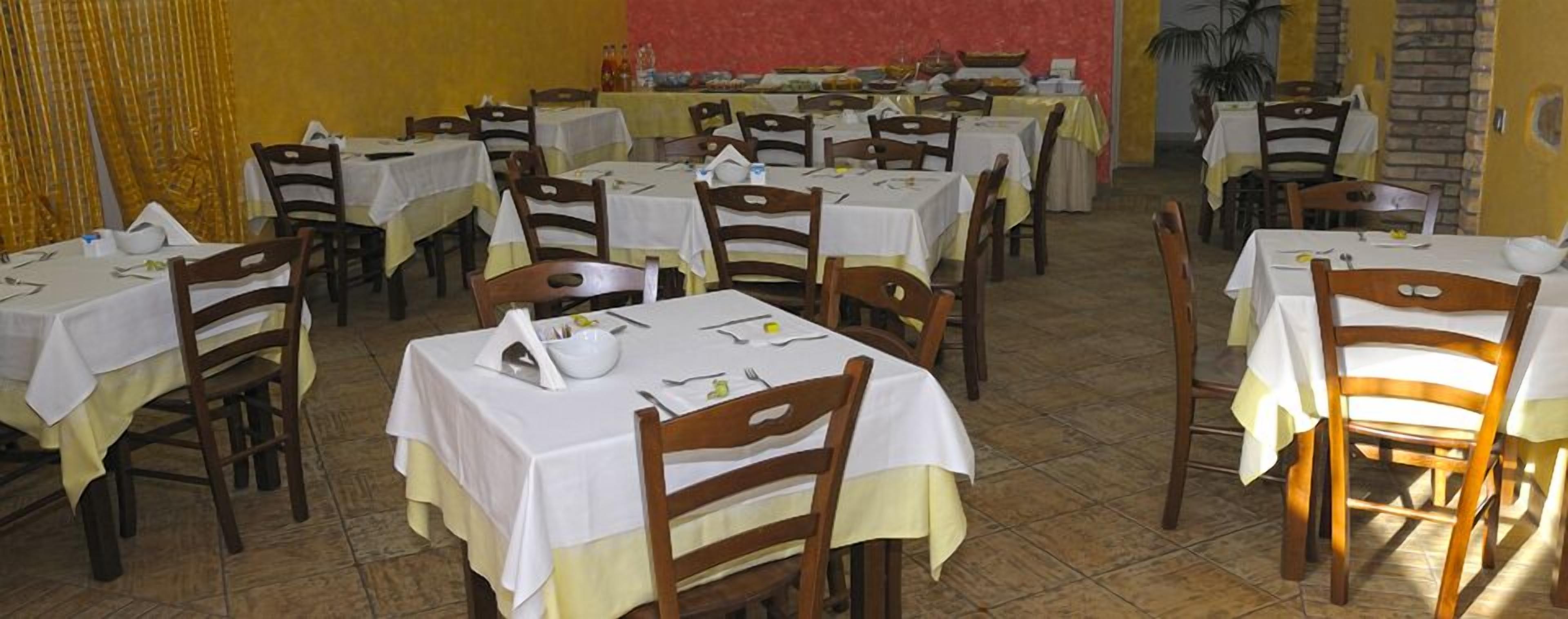 A dining area with multiple tables and chairs, arranged in rows.