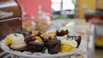 A variety of pastries on a white plate with a lace doily, placed on a metal stand.