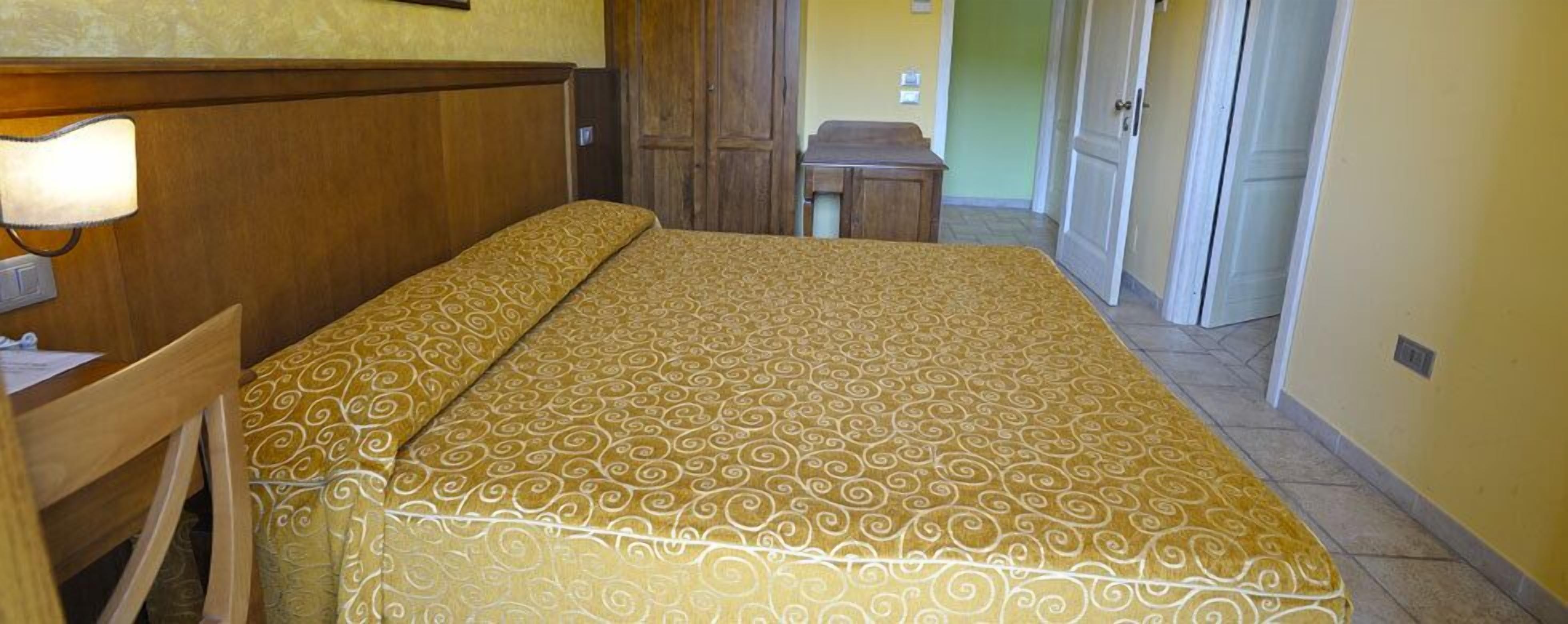 Une chambre d’hôtel avec un lit, un bureau, une lampe et une petite table.