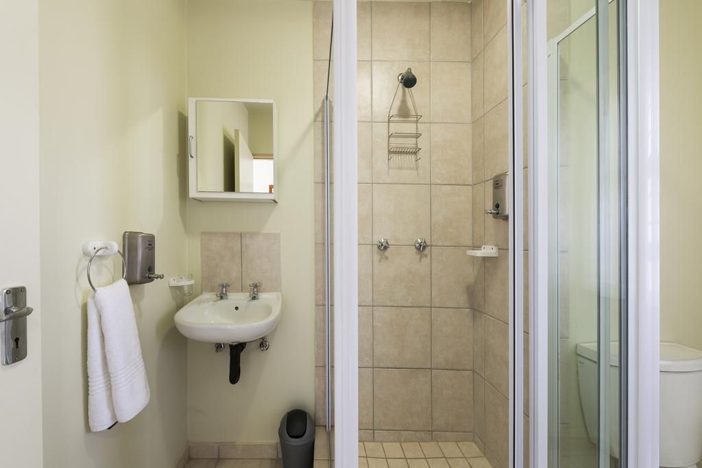Un bagno con lavandino, specchio, porta asciugamani e zona doccia con porta in vetro.