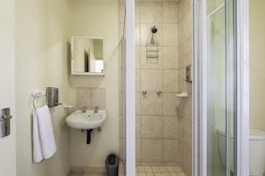 A bathroom with a sink, mirror, towel rack, and a shower area with a glass door. - Kathu Inn (Kathu)