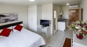 A hotel room with a bed, a TV, a desk, a kitchenette, and a bathroom. - Kathu Inn (Kathu)