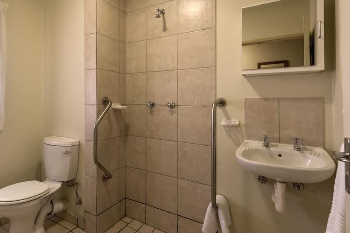 A bathroom with a toilet, shower, and sink.