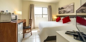A hotel room with a bed, a desk with a microwave, a chair, and a TV. - Kathu Inn (Kathu)