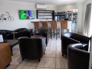 A bar area with a television, bar stools, and a refrigerator. - Kathu Inn (Kathu)