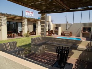 An outdoor seating area with a pool, covered by a pergola, and a sign for Kathu Inn. - Kathu Inn (Kathu)