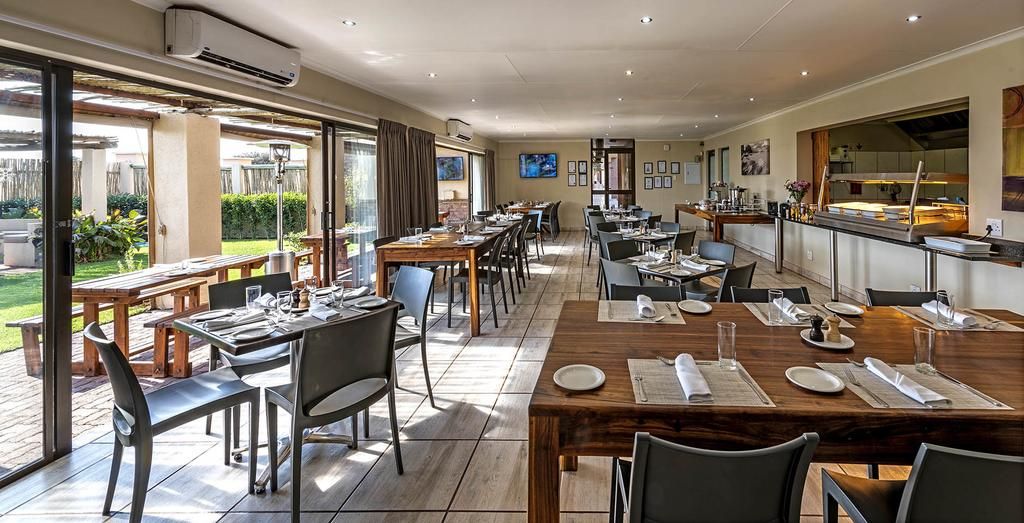 Un ristorante con posti a sedere all'aperto, una cucina visibile tramite un vetro divisorio e un televisore montato sulla parete.