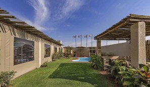 A backyard with a swimming pool, two covered structures, and a well-maintained lawn.