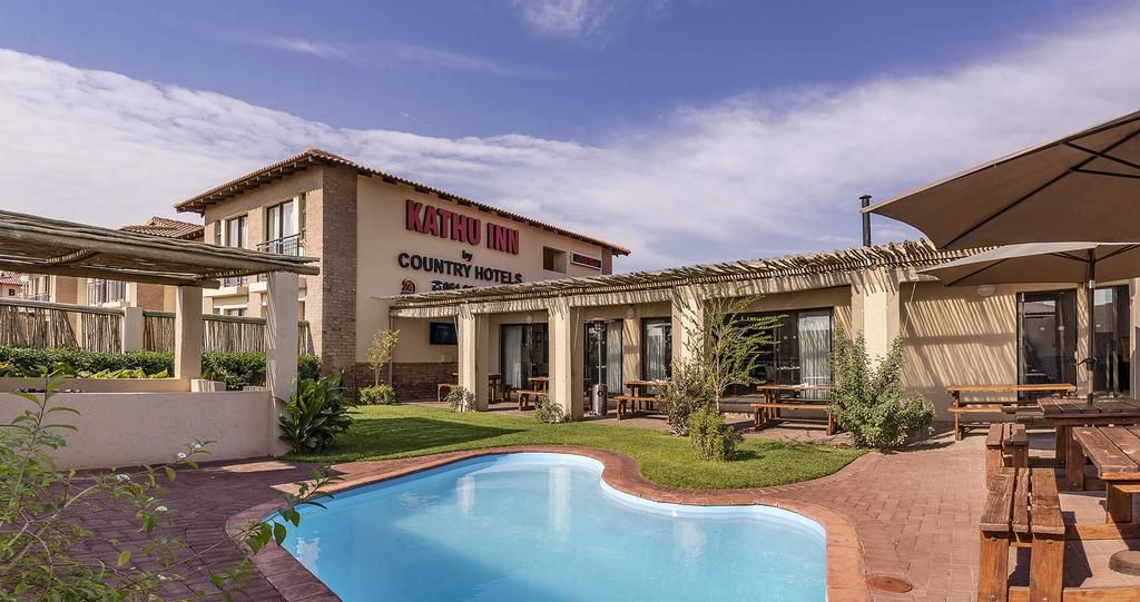 A pool area with a building labeled 'KATHU INN COUNTRY HOTELS' in the background.