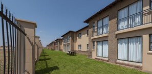 A row of townhouses with a paved walkway, a picnic table, and a clear sky. - Kathu Inn (Kathu)
