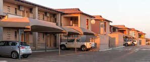 Fila de edificios de hotel con estacionamiento techado y un coche estacionado al frente.
