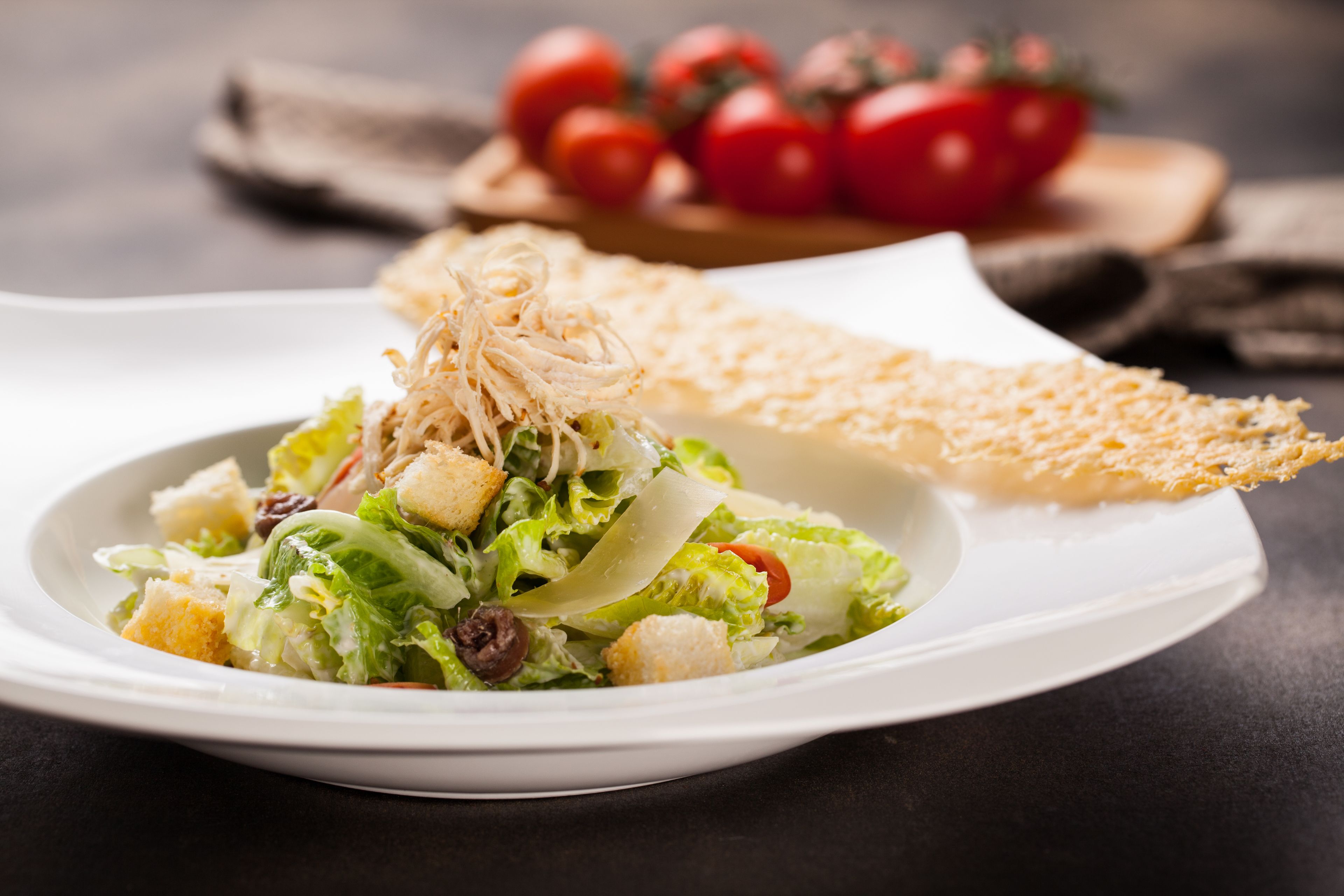 Une assiette de salade avec des croûtons et une tranche de pain, le tout servi sur une assiette blanche.