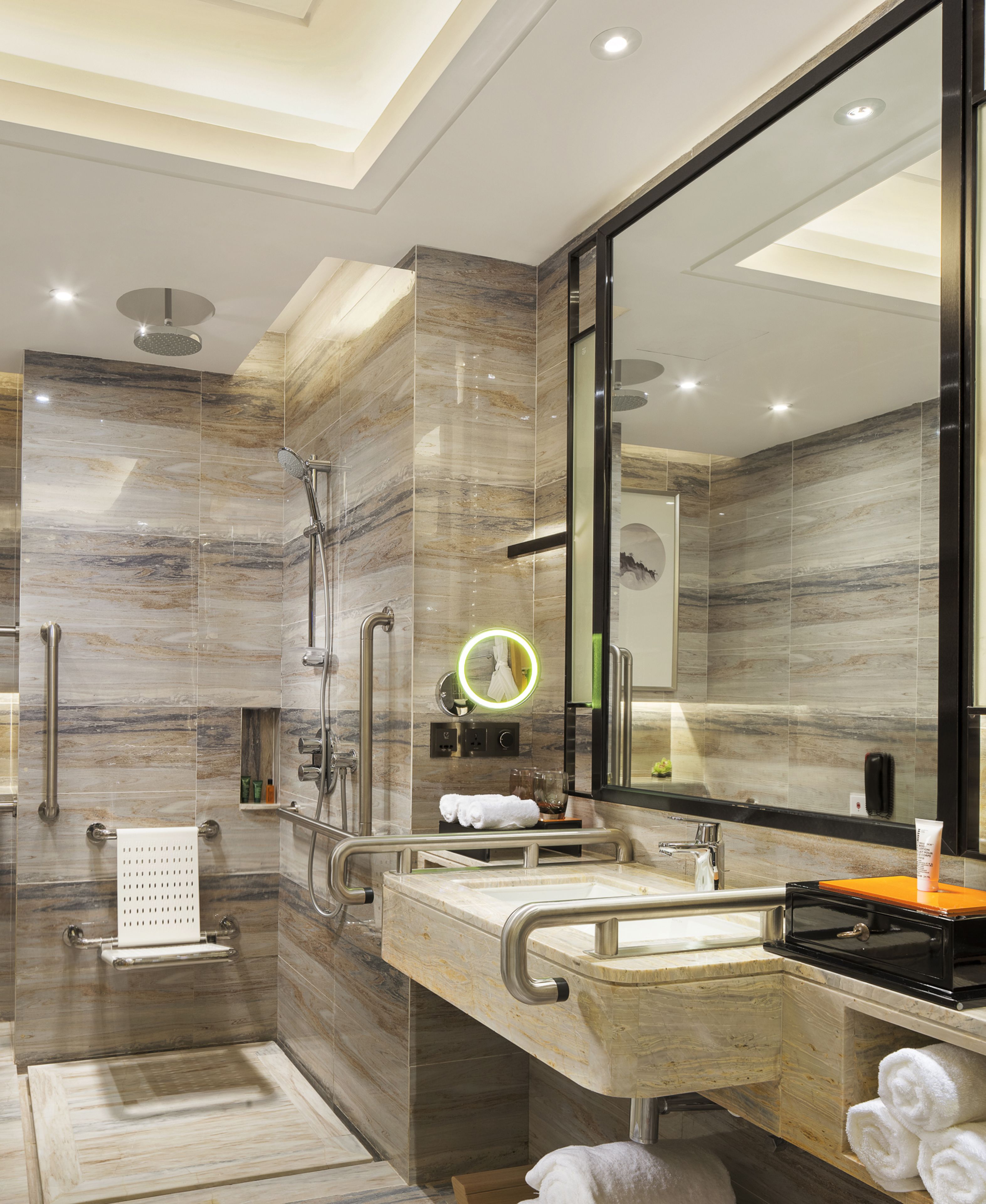 Une salle de bain moderne avec une douche à l’italienne, un meuble-lavabo avec un miroir et un porte-serviettes.