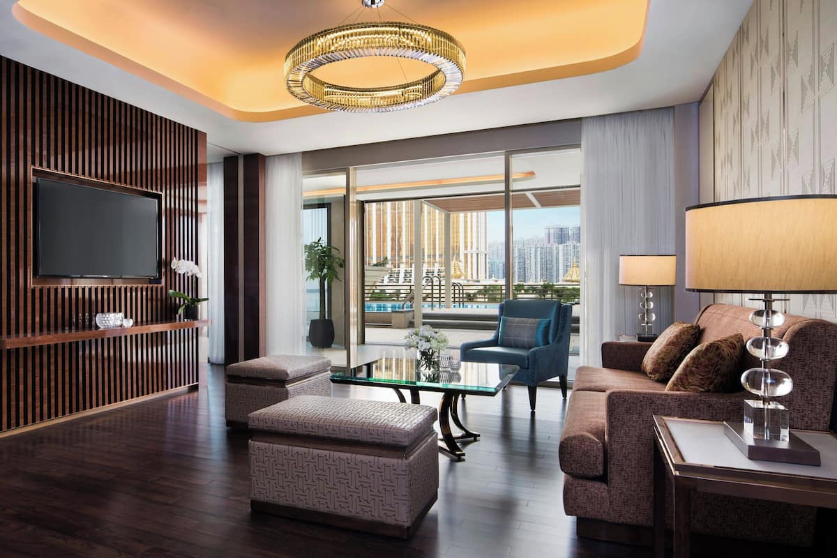 A modern living room with a flat-screen TV, a glass coffee table, a sofa, and a lamp.
