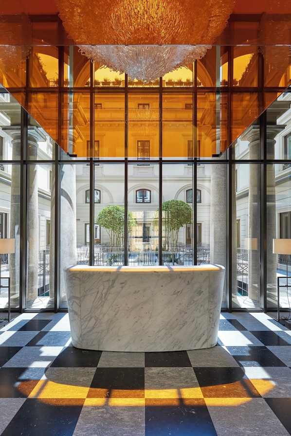 A marble bathtub in a lobby with large windows, checkered floor, and a chandelier. - Mandarin Oriental, Milan (Milan)