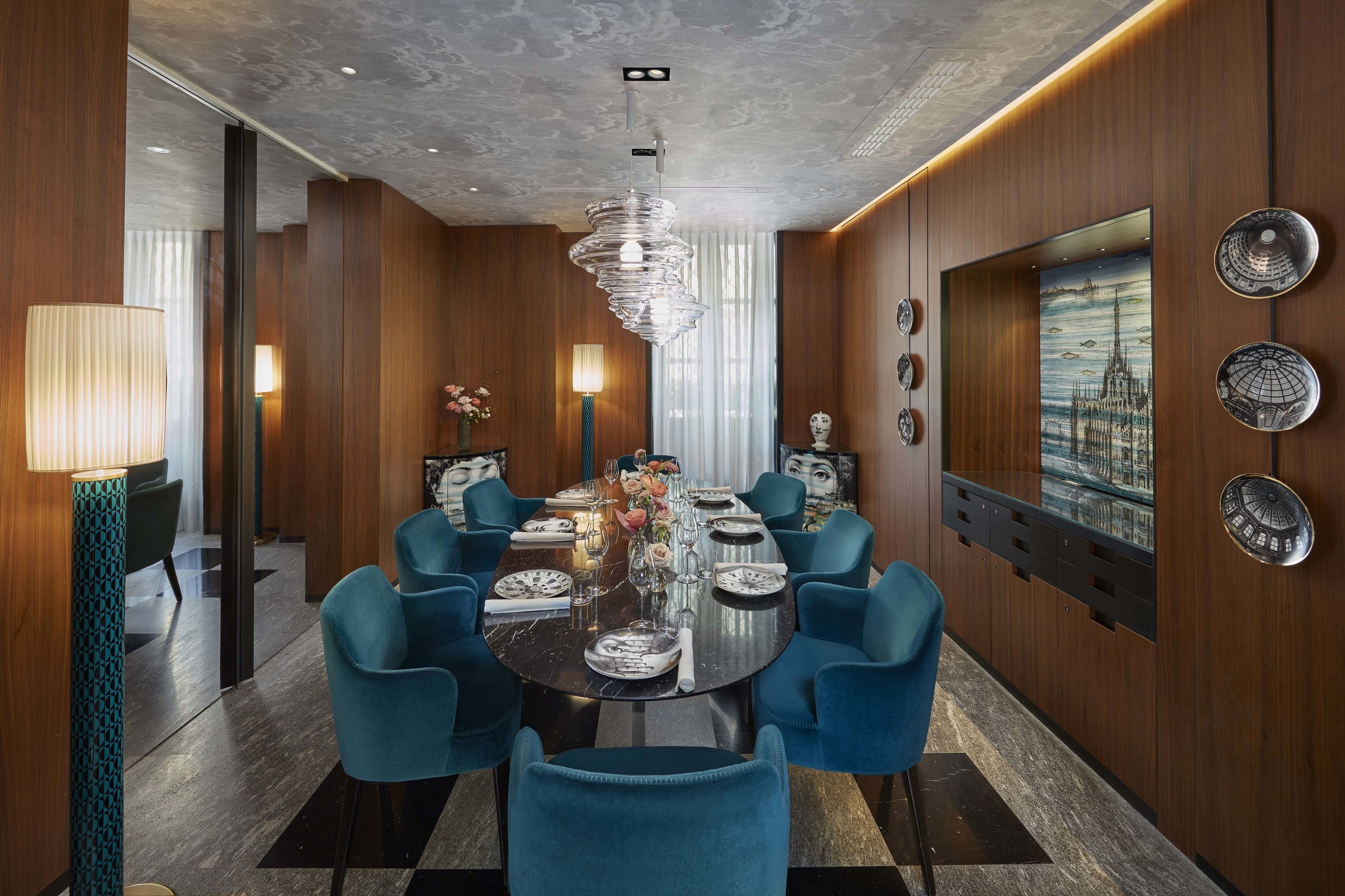 Una sala da pranzo moderna con un tavolo rotondo, sedie blu e un lampadario.