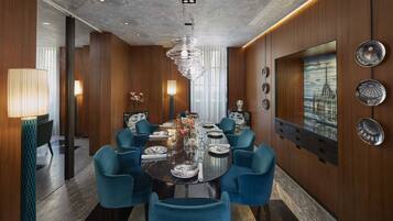 Una sala da pranzo moderna con un tavolo rotondo, sedie blu e un lampadario.