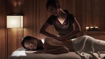 En massagebehandling i ett svagt upplyst rum med träpanel och en massageställ.