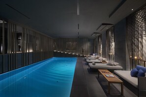 A modern indoor swimming pool with a long, narrow design, surrounded by a series of lounge areas with sofas and tables. - Mandarin Oriental, Milan (Milan)