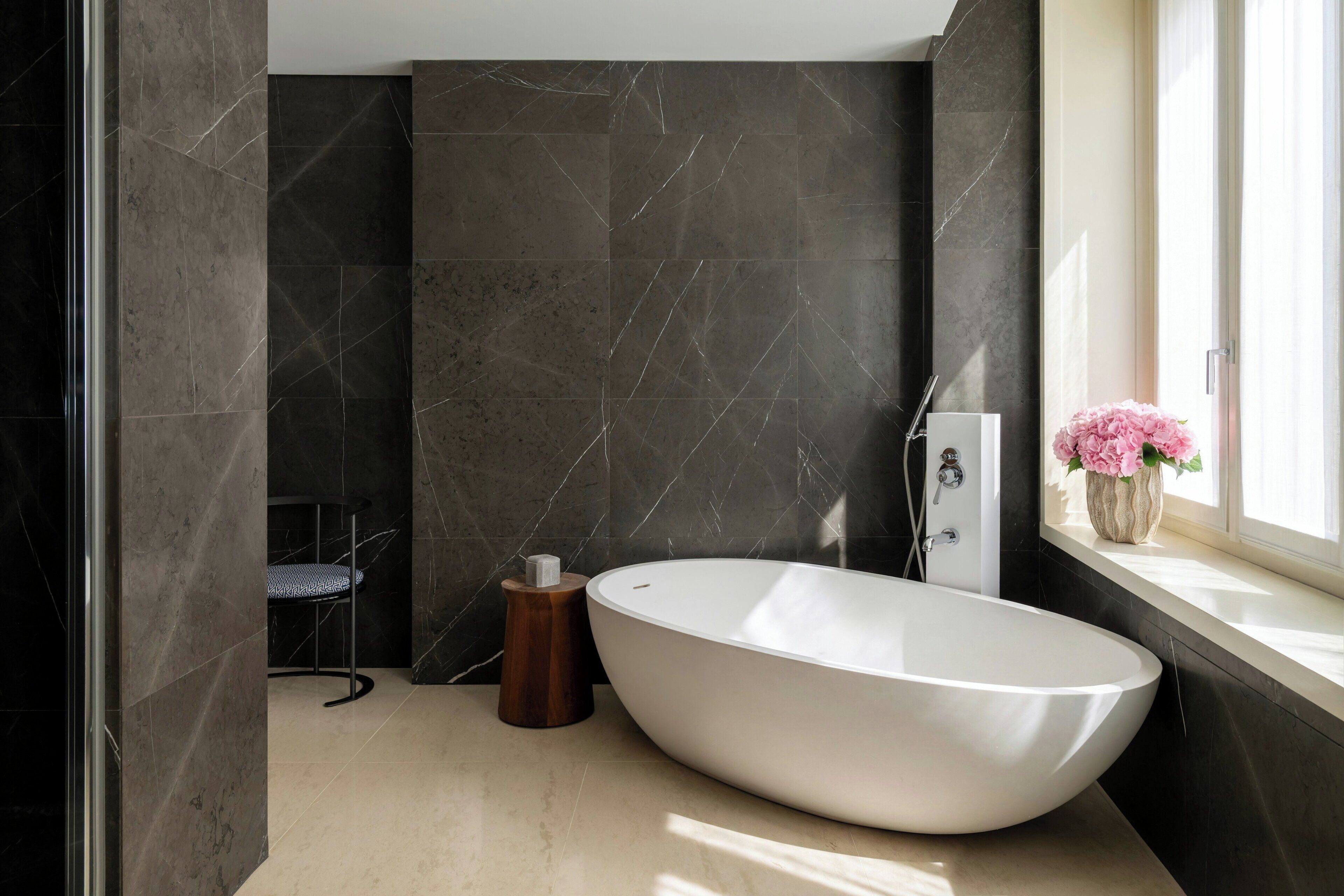 Een moderne badkamer met een vrijstaand bad, een raam met uitzicht en een stoel.