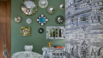 A dining area with a round table, chairs, and a wall adorned with various mirrors and decorative plates.