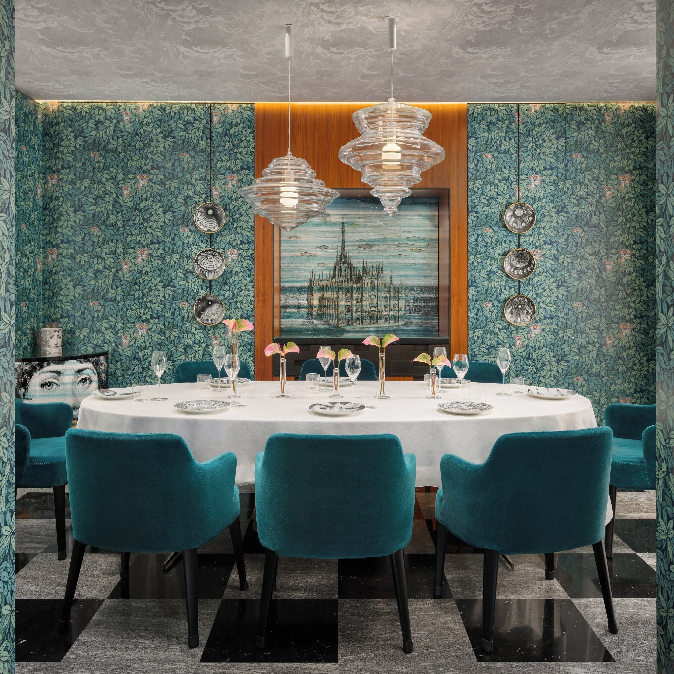 Een eetruimte met een ronde tafel voor zes personen, teal stoelen en een kroonluchter.